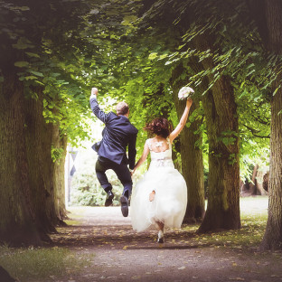 Ehepaar/Brautpaar am Springen mit Brautstrauß. Hochzeitsfoto Reinbek