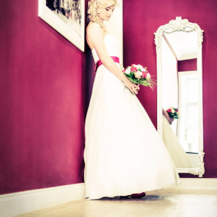 Wunderschöne Braut steht an pinker Wand