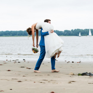 Mann trägt Braut am Strand
