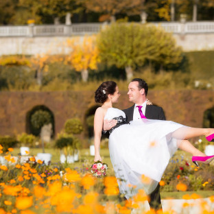 Mann trägt Braut im Rosengarten